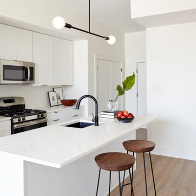 Example of a small trendy galley light wood floor and beige floor open concept kitchen design in Philadelphia with an undermount sink, flat-panel cabinets, white cabinets, quartz countertops, white backsplash, ceramic backsplash, stainless steel appliances and an island
