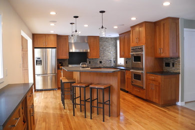 Mid-sized transitional l-shaped medium tone wood floor and brown floor open concept kitchen photo in Boston with an undermount sink, shaker cabinets, medium tone wood cabinets, concrete countertops, gray backsplash, stone tile backsplash, stainless steel appliances and an island
