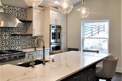 Mid-sized transitional l-shaped dark wood floor and gray floor open concept kitchen photo in Denver with a farmhouse sink, shaker cabinets, white cabinets, quartz countertops, multicolored backsplash, cement tile backsplash, stainless steel appliances, an island and white countertops