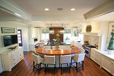 Large elegant medium tone wood floor kitchen photo in Other with white cabinets, marble countertops, stone slab backsplash and two islands
