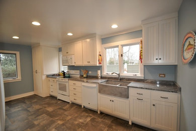 Inspiration for a mid-sized coastal galley ceramic tile and gray floor enclosed kitchen remodel in Richmond with a farmhouse sink, shaker cabinets, white cabinets, granite countertops, gray backsplash, marble backsplash and white appliances