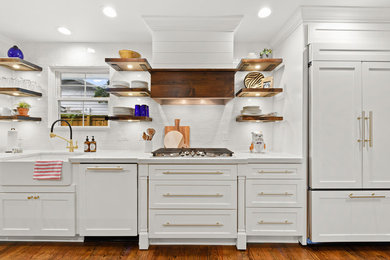 Bild på ett mellanstort funkis vit vitt kök, med en rustik diskho, skåp i shakerstil, vita skåp, bänkskiva i kvarts, vitt stänkskydd, stänkskydd i tunnelbanekakel, rostfria vitvaror, mellanmörkt trägolv, en köksö och brunt golv