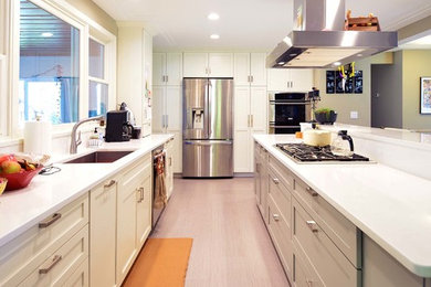 This is an example of a medium sized traditional u-shaped kitchen in Minneapolis with a single-bowl sink, flat-panel cabinets, grey cabinets, engineered stone countertops, white splashback, stainless steel appliances, porcelain flooring and an island.