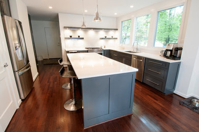 Inspiration for a medium sized contemporary l-shaped kitchen/diner in Raleigh with a submerged sink, shaker cabinets, grey cabinets, engineered stone countertops, stainless steel appliances, dark hardwood flooring, an island, white splashback and metro tiled splashback.