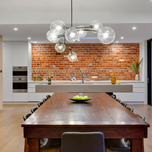 Design ideas for a large contemporary l-shaped open plan kitchen in Melbourne with an undermount sink, white cabinets, brick splashback, stainless steel appliances, with island, grey benchtop, flat-panel cabinets, red splashback, light hardwood floors and brown floor.