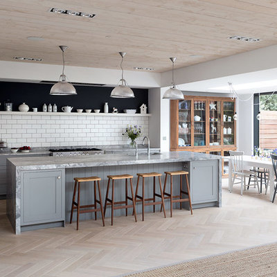 Example of a large transitional galley light wood floor and beige floor open concept kitchen design in London with an undermount sink, marble countertops, white backsplash, an island, gray countertops, shaker cabinets, gray cabinets, subway tile backsplash and stainless steel appliances
