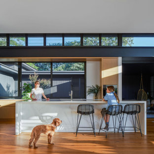 Inspiration for a contemporary eat-in kitchen in Brisbane with flat-panel cabinets, light wood cabinets, window splashback, medium hardwood floors, with island and white benchtop.