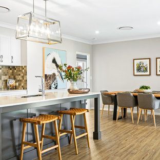 Modern eat-in kitchen in Other with a double-bowl sink, shaker cabinets, white cabinets, beige splashback, medium hardwood floors, with island, brown floor and white benchtop.