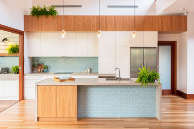 シドニーにあるトラディショナルスタイルのおしゃれなキッチン (フラットパネル扉のキャビネット、中間色木目調キャビネット、クオーツストーンカウンター、青いキッチンパネル、サブウェイタイルのキッチンパネル、シルバーの調理設備、無垢フローリング、グレーのキッチンカウンター) の写真