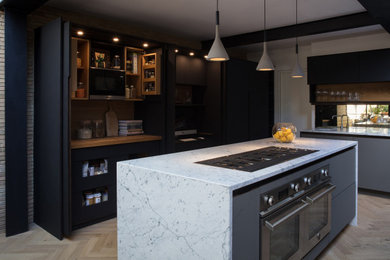 Design ideas for a large contemporary l-shaped open plan kitchen in London with a belfast sink, flat-panel cabinets, grey cabinets, laminate countertops, brown splashback, brick splashback, integrated appliances, light hardwood flooring, an island, beige floors and white worktops.