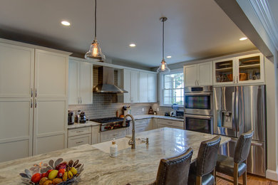 Large trendy l-shaped medium tone wood floor and brown floor enclosed kitchen photo in DC Metro with a farmhouse sink, shaker cabinets, white cabinets, quartzite countertops, gray backsplash, ceramic backsplash, stainless steel appliances, a peninsula and beige countertops
