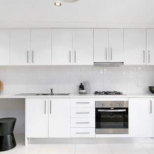 Photo of a contemporary single-wall kitchen in Sydney with a double-bowl sink, flat-panel cabinets, white cabinets, quartz benchtops, white splashback, ceramic splashback, stainless steel appliances, ceramic floors, no island, white floor and white benchtop.