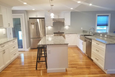 Inspiration for a mid-sized transitional u-shaped medium tone wood floor and brown floor open concept kitchen remodel in Boston with a farmhouse sink, recessed-panel cabinets, white cabinets, granite countertops, stainless steel appliances and an island