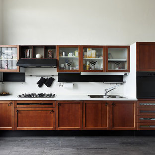 Idee per una piccola cucina lineare tradizionale chiusa con lavello da incasso, ante con riquadro incassato, ante in legno bruno, top in superficie solida, paraspruzzi bianco, paraspruzzi in lastra di pietra, elettrodomestici in acciaio inossidabile, pavimento in vinile, nessuna isola, pavimento nero e top bianco
