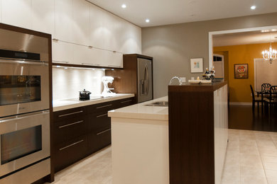 Foto di una cucina minimalista di medie dimensioni con lavello a doppia vasca, ante lisce, ante bianche, top in granito, paraspruzzi grigio, elettrodomestici in acciaio inossidabile e pavimento con piastrelle in ceramica