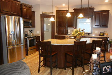 Enclosed kitchen - mid-sized traditional l-shaped light wood floor and beige floor enclosed kitchen idea in Cedar Rapids with an undermount sink, raised-panel cabinets, dark wood cabinets, quartz countertops, stainless steel appliances and an island