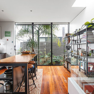 Beach style single-wall kitchen in Melbourne with flat-panel cabinets, grey cabinets, wood benchtops, white splashback, stainless steel appliances, medium hardwood floors, with island, brown floor and brown benchtop.