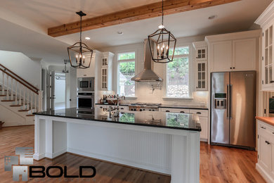 Inspiration for a large craftsman galley light wood floor open concept kitchen remodel in Raleigh with a farmhouse sink, recessed-panel cabinets, white cabinets, granite countertops, white backsplash, ceramic backsplash, stainless steel appliances and an island