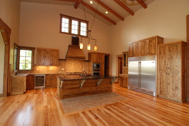 Rustik inredning av ett stort kök, med en undermonterad diskho, luckor med infälld panel, skåp i mellenmörkt trä, granitbänkskiva, beige stänkskydd, stänkskydd i stenkakel, rostfria vitvaror, mellanmörkt trägolv och en köksö