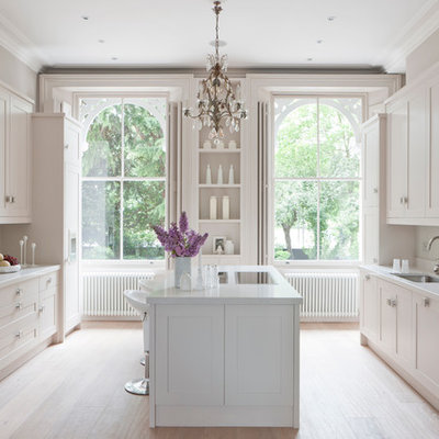 Inspiration for a transitional kitchen remodel in London with recessed-panel cabinets, white cabinets, white backsplash, glass sheet backsplash and paneled appliances