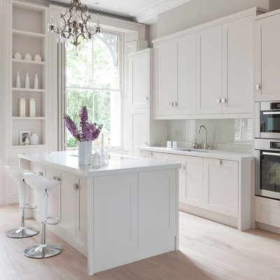 Inspiration for a contemporary kitchen remodel in London with an undermount sink, shaker cabinets, white backsplash, glass sheet backsplash, stainless steel appliances and white cabinets