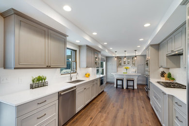 Example of a transitional galley vinyl floor and brown floor eat-in kitchen design in Denver with a double-bowl sink, shaker cabinets, gray cabinets, quartz countertops, multicolored backsplash, marble backsplash, stainless steel appliances, an island and white countertops