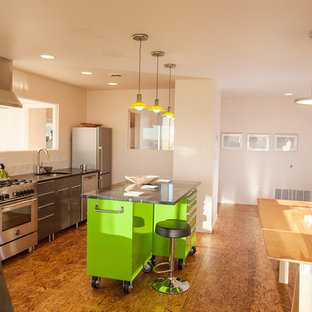 Foto de cocina comedor lineal, actual, pequeña, con fregadero bajoencimera, armarios con paneles lisos, puertas de armario grises, encimera de esteatita, salpicadero blanco, salpicadero de azulejos de cerámica, electrodomésticos de acero inoxidable, suelo de contrachapado y una isla
