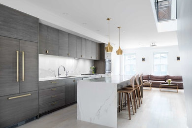 Example of a mid-sized minimalist galley light wood floor and white floor open concept kitchen design in New York with a single-bowl sink, flat-panel cabinets, medium tone wood cabinets, solid surface countertops, white backsplash, stone slab backsplash, paneled appliances and an island