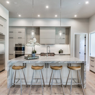 Large mediterranean kitchen designs - Inspiration for a large mediterranean l-shaped light wood floor kitchen remodel in Dallas with a drop-in sink, flat-panel cabinets, white cabinets, marble countertops, white backsplash, stainless steel appliances, an island and multicolored countertops