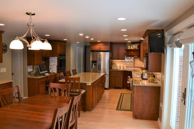 Huge u-shaped light wood floor and beige floor eat-in kitchen photo in New York with a double-bowl sink, recessed-panel cabinets, dark wood cabinets, granite countertops, multicolored backsplash, mosaic tile backsplash, stainless steel appliances and an island