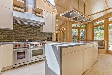 Photo of a medium sized contemporary l-shaped kitchen/diner in Hertfordshire with an integrated sink, flat-panel cabinets, white cabinets, composite countertops, white splashback, wood splashback, stainless steel appliances, limestone flooring, an island and white floors.