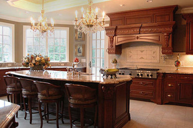 This is an example of a large traditional u-shaped open plan kitchen in New York with a submerged sink, beaded cabinets, medium wood cabinets, engineered stone countertops, beige splashback, travertine splashback, stainless steel appliances, travertine flooring, an island and beige floors.