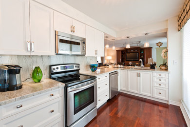 Example of a classic kitchen design in Toronto with recessed-panel cabinets, stainless steel appliances and stone slab backsplash
