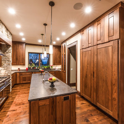 Inspiration for a rustic u-shaped dark wood floor and brown floor kitchen remodel in Other with an undermount sink, shaker cabinets, dark wood cabinets, paneled appliances, an island and gray countertops