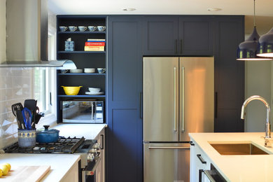 Exempel på ett mellanstort modernt l-kök, med en undermonterad diskho, blå skåp, bänkskiva i kvarts, vitt stänkskydd, stänkskydd i keramik, rostfria vitvaror, mellanmörkt trägolv och en köksö