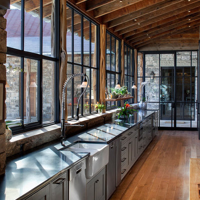 Example of a mountain style single-wall medium tone wood floor kitchen design in Austin with a farmhouse sink, gray cabinets, shaker cabinets and stainless steel appliances