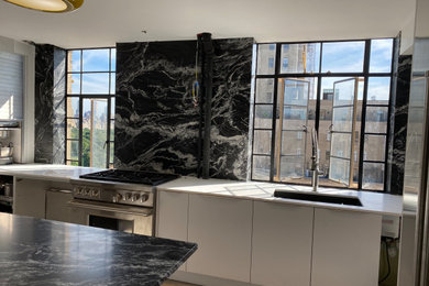 Kitchen - large traditional kitchen idea in New York with flat-panel cabinets, white cabinets, quartz countertops, black backsplash and granite backsplash