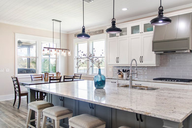 Transitional l-shaped brown floor open concept kitchen photo in Jacksonville with an undermount sink, shaker cabinets, white cabinets, gray backsplash, subway tile backsplash, stainless steel appliances and an island