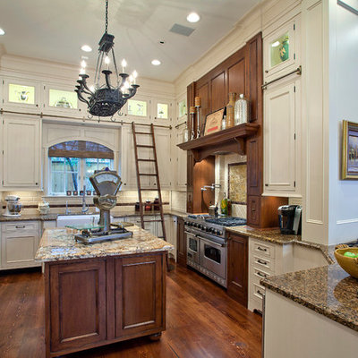 Large elegant u-shaped medium tone wood floor and brown floor enclosed kitchen photo in Houston with recessed-panel cabinets, white cabinets, stainless steel appliances, a farmhouse sink, granite countertops, subway tile backsplash, an island and white backsplash