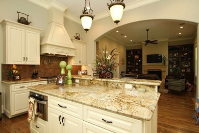 Diseño de cocina clásica con una isla, puertas de armario beige, electrodomésticos de acero inoxidable y suelo de madera en tonos medios