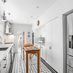 Design ideas for a mid-sized victorian galley separate kitchen in Sydney with an undermount sink, recessed-panel cabinets, white cabinets, solid surface benchtops, marble splashback, stainless steel appliances, ceramic floors, white benchtop, with island, white splashback and white floor.