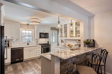 Example of a mid-sized classic u-shaped laminate floor and gray floor eat-in kitchen design in Other with an undermount sink, shaker cabinets, white cabinets, granite countertops, white backsplash, subway tile backsplash, black appliances and a peninsula