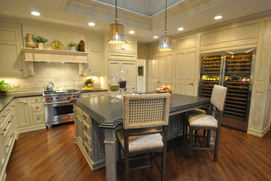 Eat-in kitchen - mid-sized traditional u-shaped dark wood floor eat-in kitchen idea in Columbus with a farmhouse sink, recessed-panel cabinets, light wood cabinets, beige backsplash, ceramic backsplash, stainless steel appliances and an island