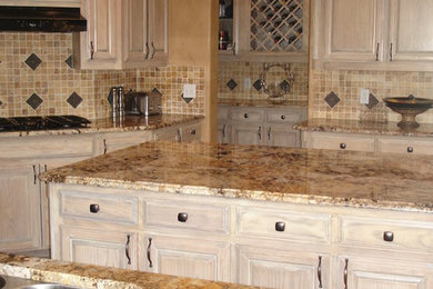 Exempel på ett klassiskt kök, med en undermonterad diskho, luckor med upphöjd panel, granitbänkskiva, stänkskydd i stenkakel, rostfria vitvaror och en köksö