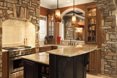 Mid-sized elegant l-shaped ceramic tile kitchen photo in Other with a farmhouse sink, raised-panel cabinets, medium tone wood cabinets, granite countertops, beige backsplash, ceramic backsplash, stainless steel appliances and an island