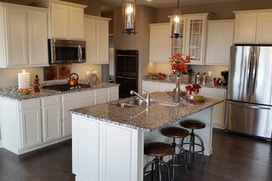 Example of a mid-sized transitional dark wood floor eat-in kitchen design in St Louis with a double-bowl sink, recessed-panel cabinets, white cabinets, granite countertops, white backsplash, stone slab backsplash, stainless steel appliances and an island