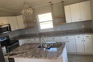 Example of a mid-sized cottage l-shaped medium tone wood floor and brown floor open concept kitchen design in Miami with a double-bowl sink, shaker cabinets, white cabinets, granite countertops, stainless steel appliances, an island and brown countertops
