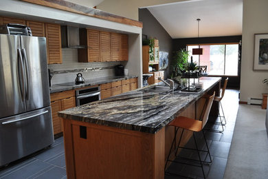 Exempel på ett mellanstort modernt linjärt kök och matrum, med en undermonterad diskho, skåp i ljust trä, granitbänkskiva, grått stänkskydd, stänkskydd i keramik, rostfria vitvaror, klinkergolv i porslin och en köksö