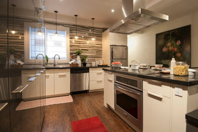Bild på ett mellanstort funkis kök, med släta luckor, grå skåp, bänkskiva i kvarts, grått stänkskydd, en köksö, en undermonterad diskho, stänkskydd i mosaik, integrerade vitvaror och mellanmörkt trägolv