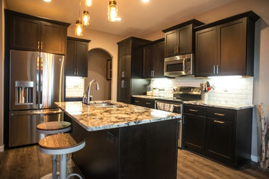 Example of a large eclectic single-wall medium tone wood floor eat-in kitchen design in Other with an undermount sink, shaker cabinets, dark wood cabinets, granite countertops, white backsplash, glass tile backsplash, stainless steel appliances and an island
